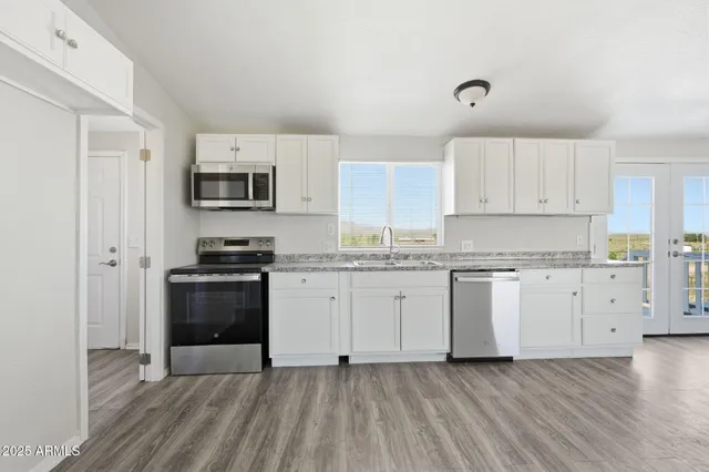 a kitchen with granite countertop white cabinets and stainless steel appliances