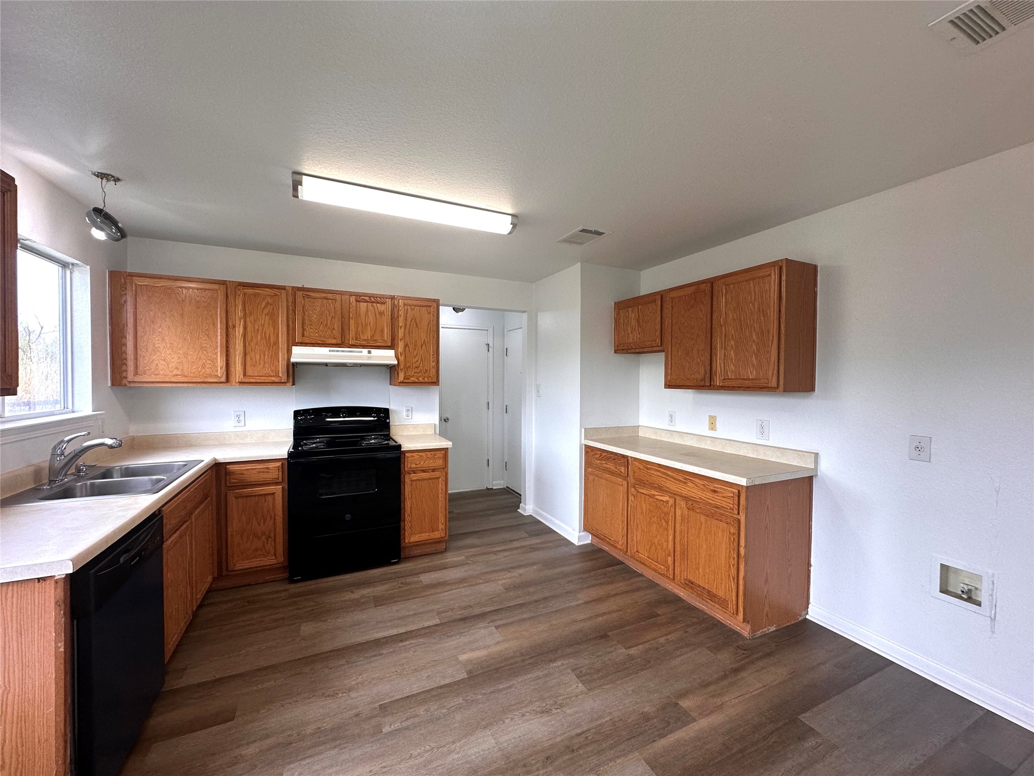 722 Lavaca Loop Elgin, TX 78621 - Photo 6 of 24 Kitchen with black appliances, light countertops, wood finish cabinetry, and dark wood-style flooring