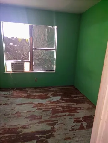 a view of empty room with window and wooden floor