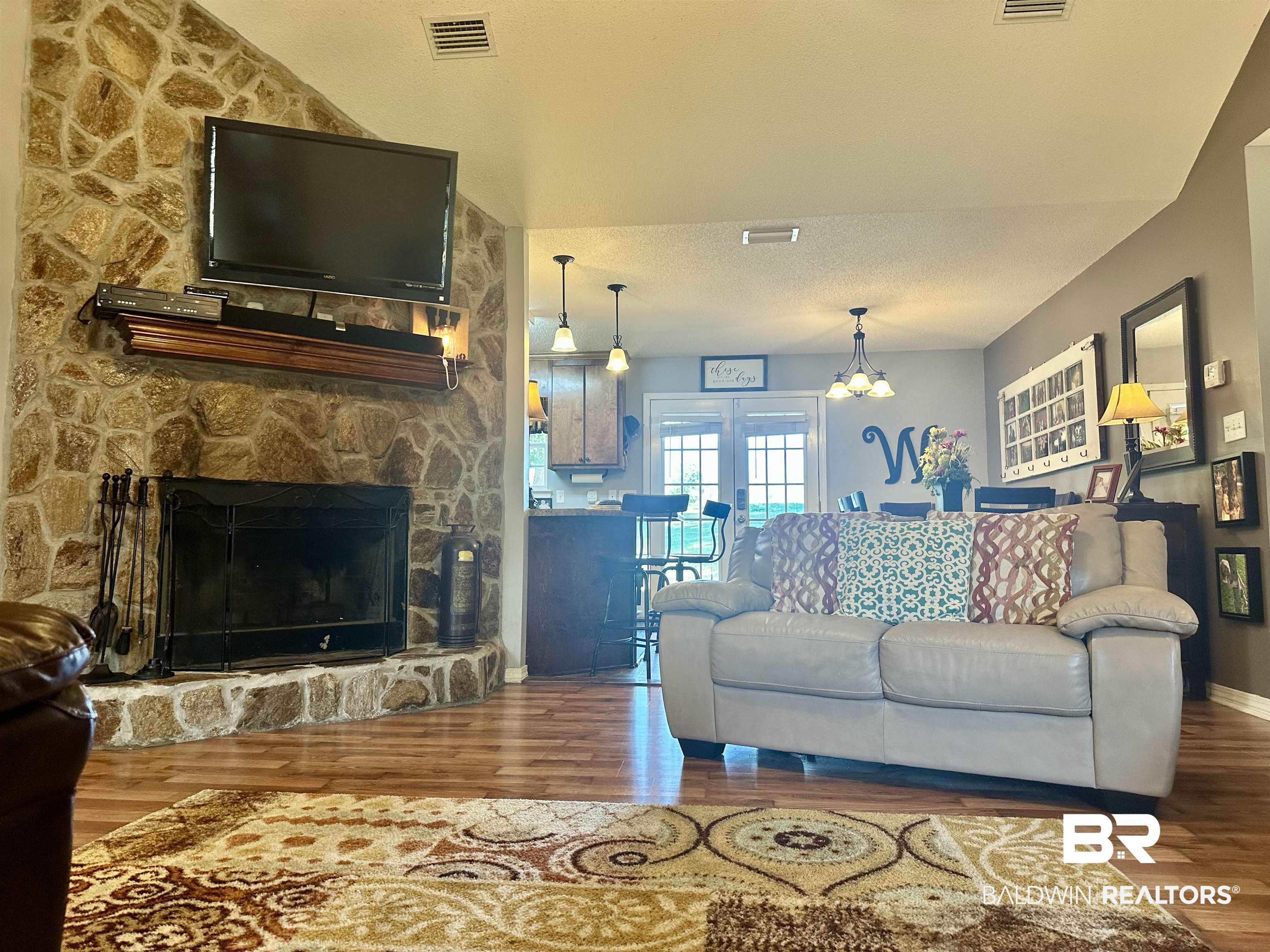 2456 Smith Road Castleberry, AL 36432 - Photo 3 of 26 Living room with a fireplace, hardwood / wood-style floors, a chandelier, and a textured ceiling