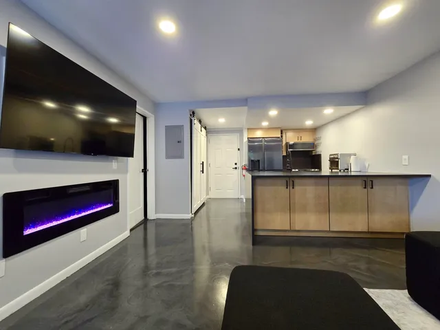 a open kitchen with stainless steel appliances kitchen island granite countertop a refrigerator a stove and a sink with wooden floor