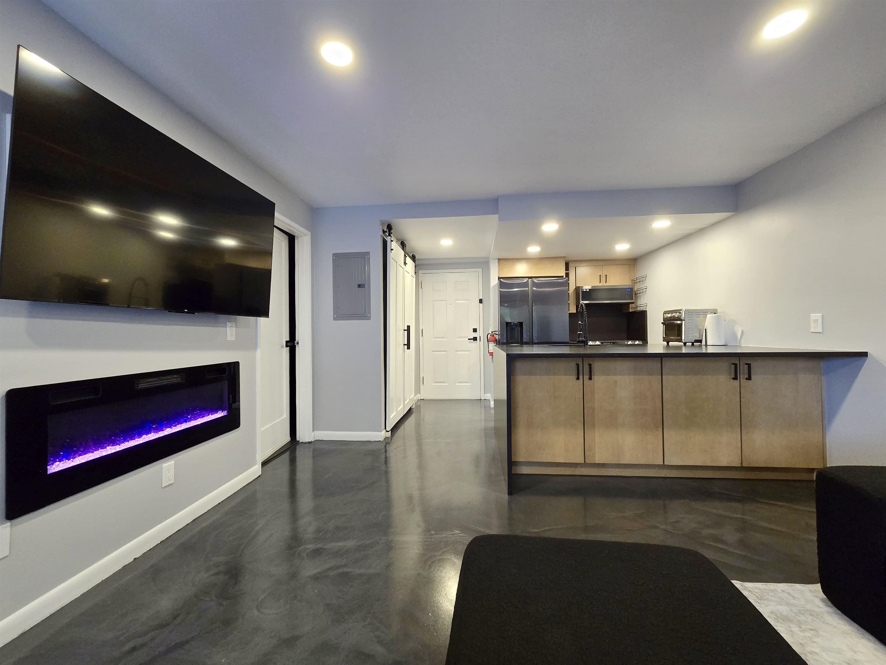 a open kitchen with stainless steel appliances kitchen island granite countertop a refrigerator a stove and a sink with wooden floor