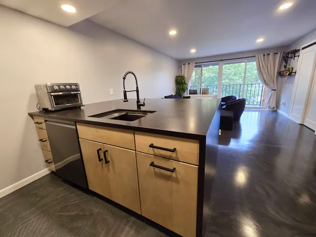 a kitchen with stainless steel appliances granite countertop a sink a stove a dining table and chairs with wooden floor