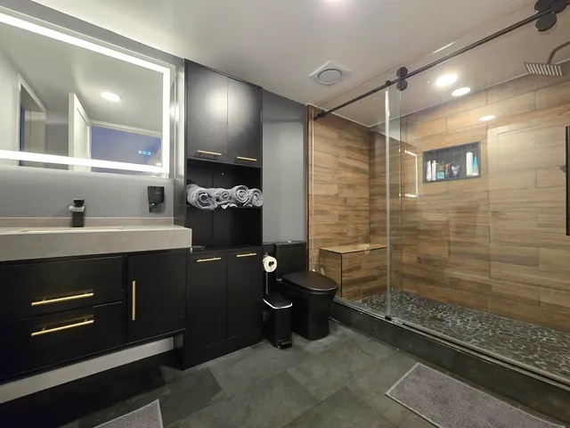 a bathroom with a sink a toilet a mirror and shower