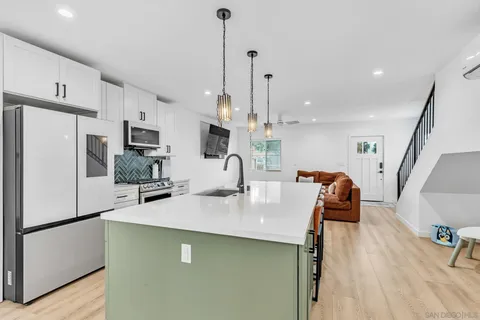 a kitchen with stainless steel appliances a refrigerator a sink a stove a microwave a center island and chairs