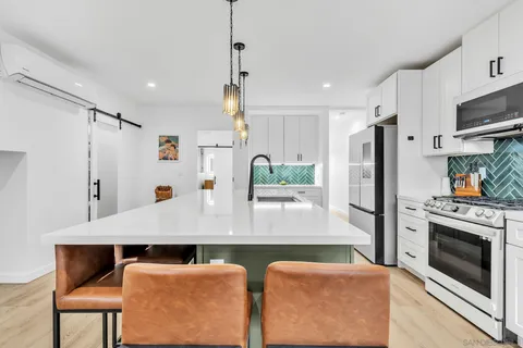 a kitchen with stainless steel appliances granite countertop a refrigerator a stove and white cabinets with wooden floors