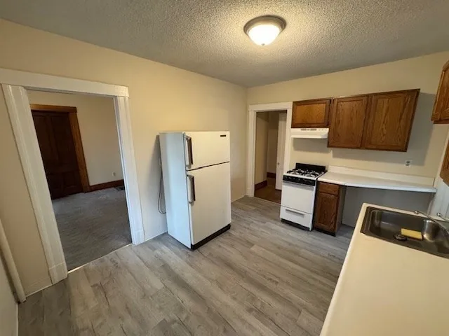 a kitchen with a refrigerator a stove and wooden floor