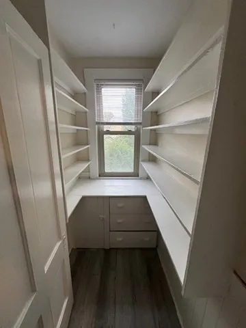 a view of walk in closet with wooden floor and cabinet