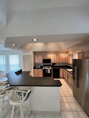 a kitchen with stainless steel appliances granite countertop a refrigerator a sink a stove a dining table and chairs