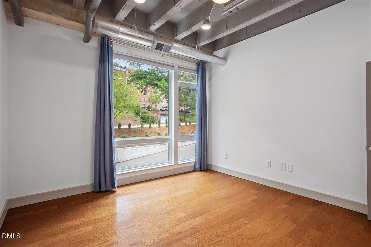 1300 St Marys Street, Unit 207 Raleigh, NC 27605 - Photo 11 of 31 an empty room with wooden floor and windows