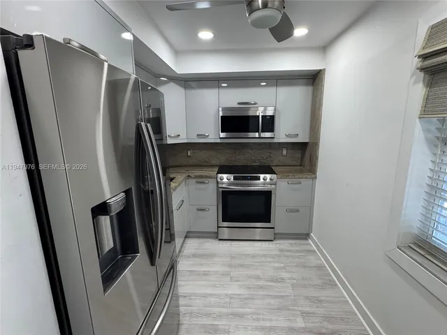 a view of a refrigerator in kitchen and microwave