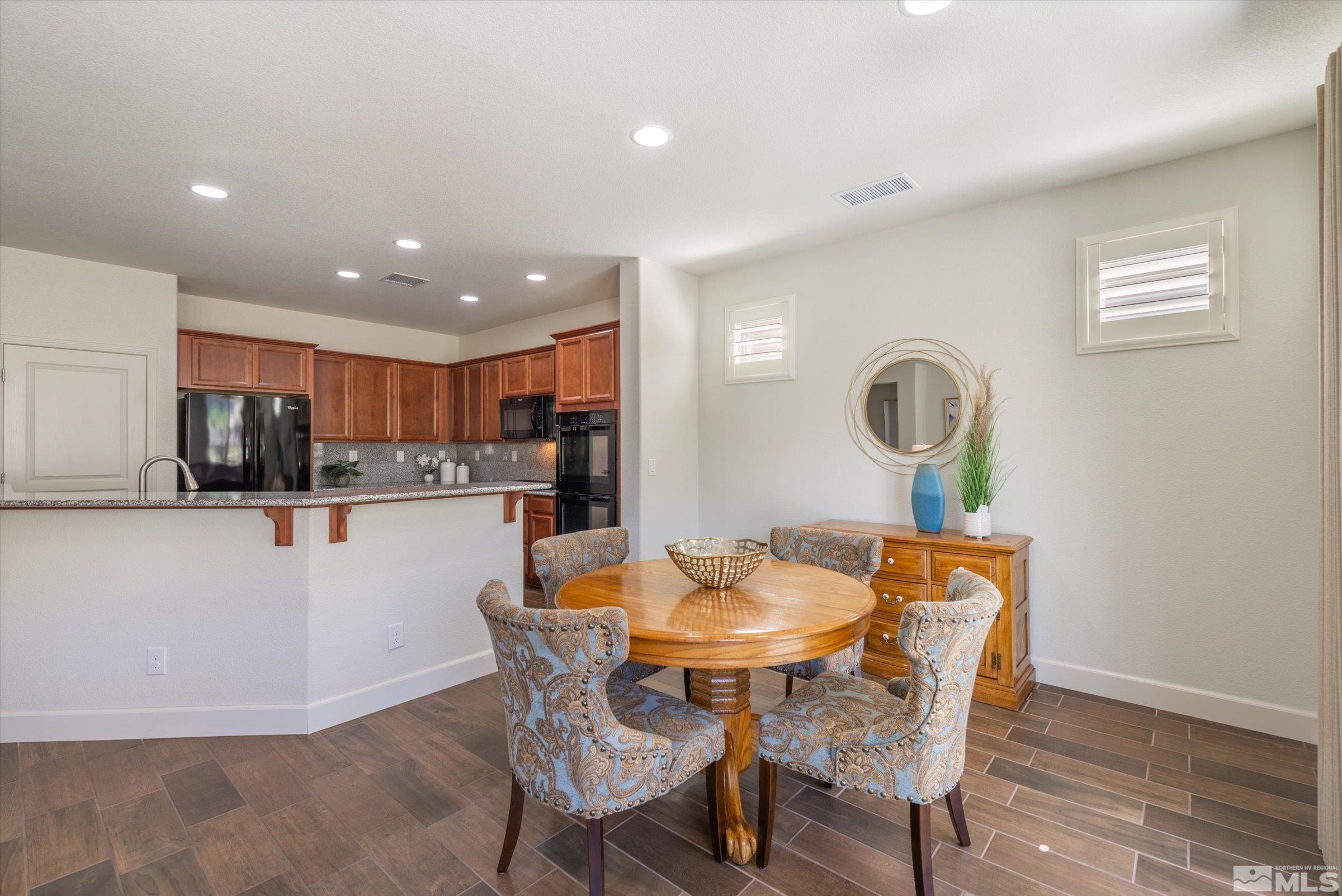 9207 Maplehurst Trail Reno, NV 89523 - Photo 13 of 40 a kitchen with stainless steel appliances kitchen island granite countertop a dining table chairs and a refrigerator a sink with wooden floor