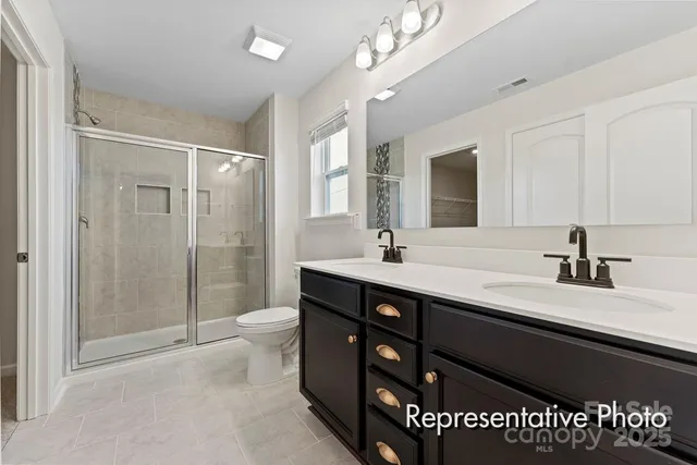 a spacious bathroom with a double vanity sink a toilet a mirror and shower