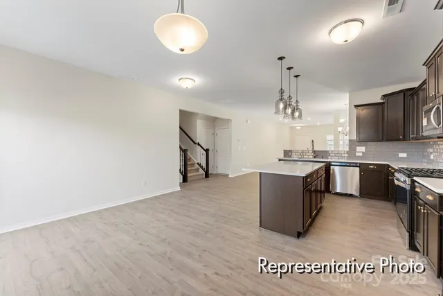 an open kitchen with a sink and dishwasher a stove top oven with wooden floor