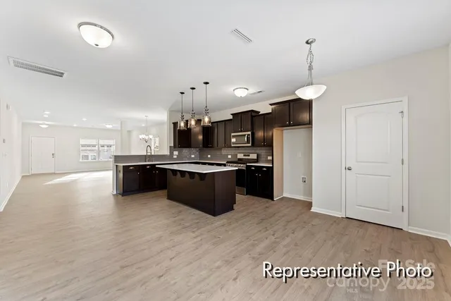 a kitchen with stainless steel appliances kitchen island granite countertop a sink a stove and a wooden floors