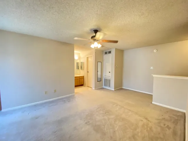 an empty room with windows and a ceiling fan