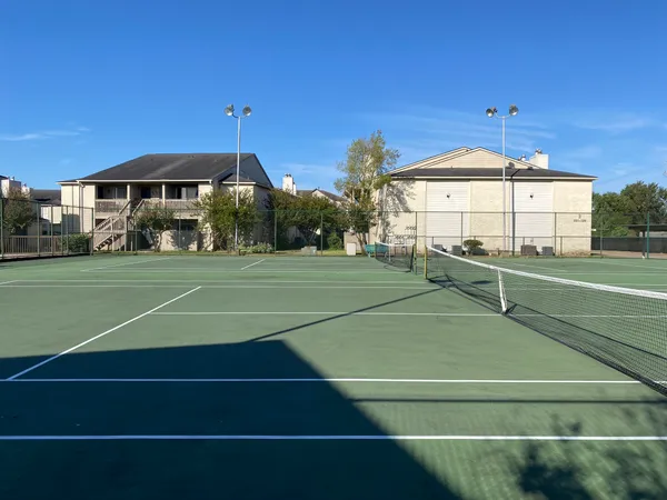 a view of a tennis ground with large trees