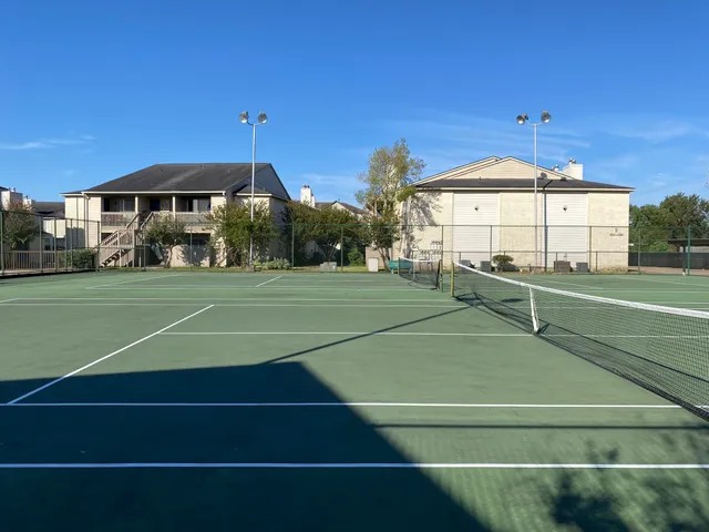 a view of a tennis ground with large trees