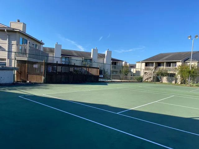 a view of a tennis ground with large trees