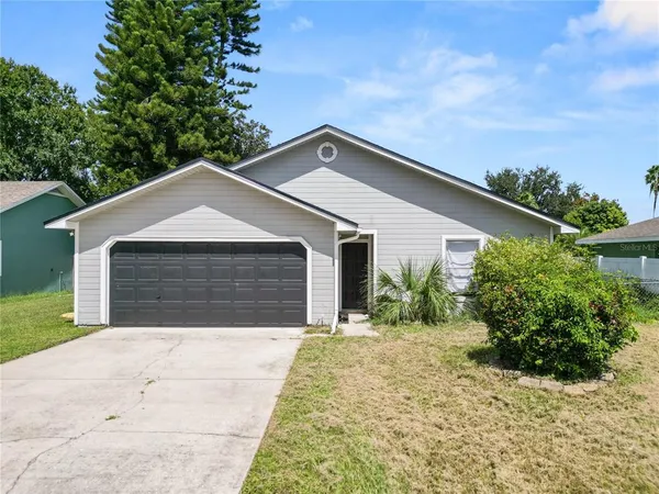 a front view of house with yard and trees in the background