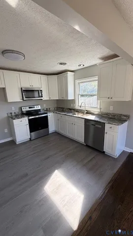 a kitchen with stainless steel appliances granite countertop a stove a sink and a microwave