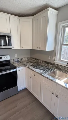 a kitchen with granite countertop white cabinets and stainless steel appliances