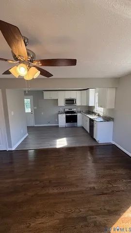 a view of kitchen and empty room with wooden floor