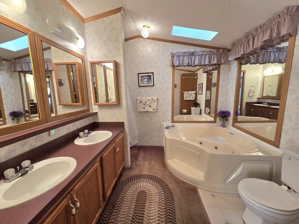 268 Palmer Road, Unit 59 Monson, MA 01057 - Photo 12 of 27 a spacious bathroom with a granite countertop sink a toilet a mirror a vanity a bathtub and shower