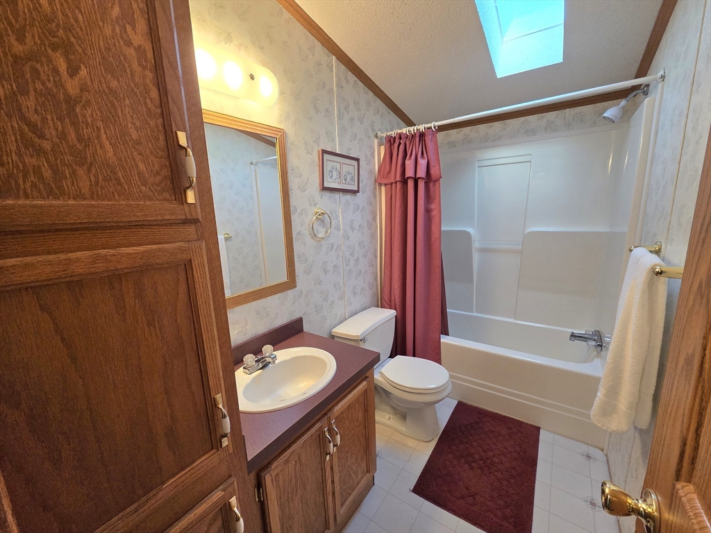 268 Palmer Road, Unit 59 Monson, MA 01057 - Photo 17 of 27 a bathroom with a sink a toilet a mirror a vanity and shower