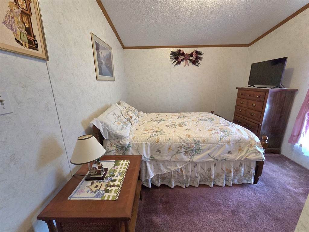 268 Palmer Road, Unit 59 Monson, MA 01057 - Photo 18 of 27 a bedroom with a bed a couch and a potted plant