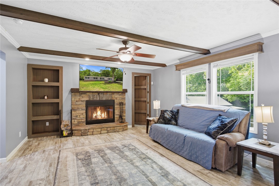 119 Fruit Mountain Road Easley, SC 29640 - Photo 3 of 31 This inviting living space features an exposed beam ceiling and a cozy fireplace, creating a warm atmosphere.