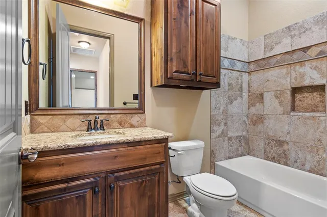 a bathroom with a granite countertop toilet sink and mirror