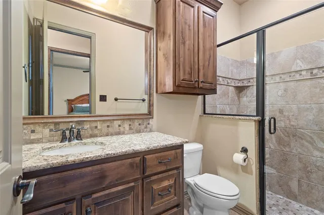 a bathroom with a granite countertop sink a toilet and a mirror