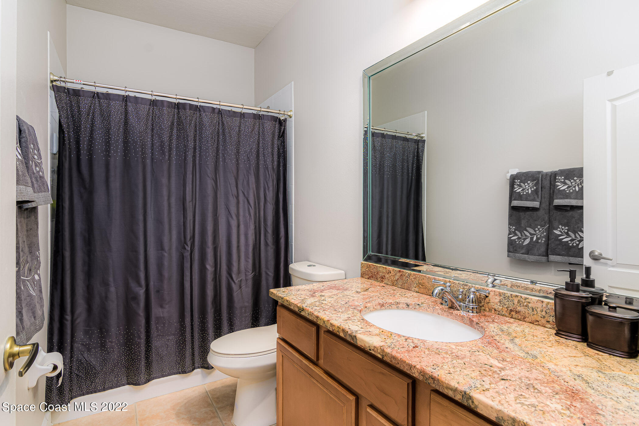 3832 Stream Drive Melbourne, FL 32940 - Photo 25 of 63 a bathroom with a granite countertop sink toilet and mirror