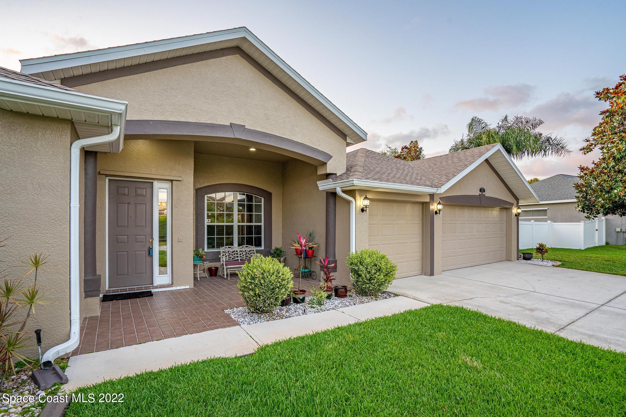 3832 Stream Drive Melbourne, FL 32940 - Photo 46 of 63 a view of a white house next to a yard with potted plants