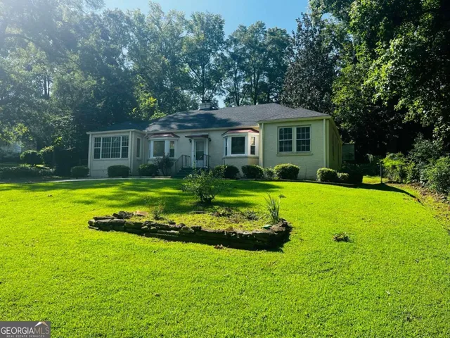 a view of a house with a big yard potted plants and large trees