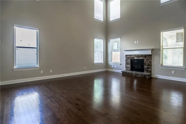 an empty room with wooden floor fireplace and windows