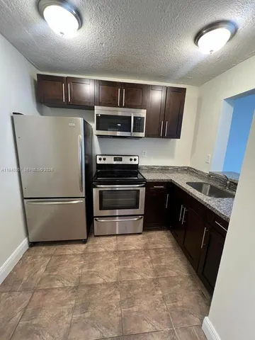 a kitchen with stainless steel appliances granite countertop a refrigerator a stove a sink and a microwave