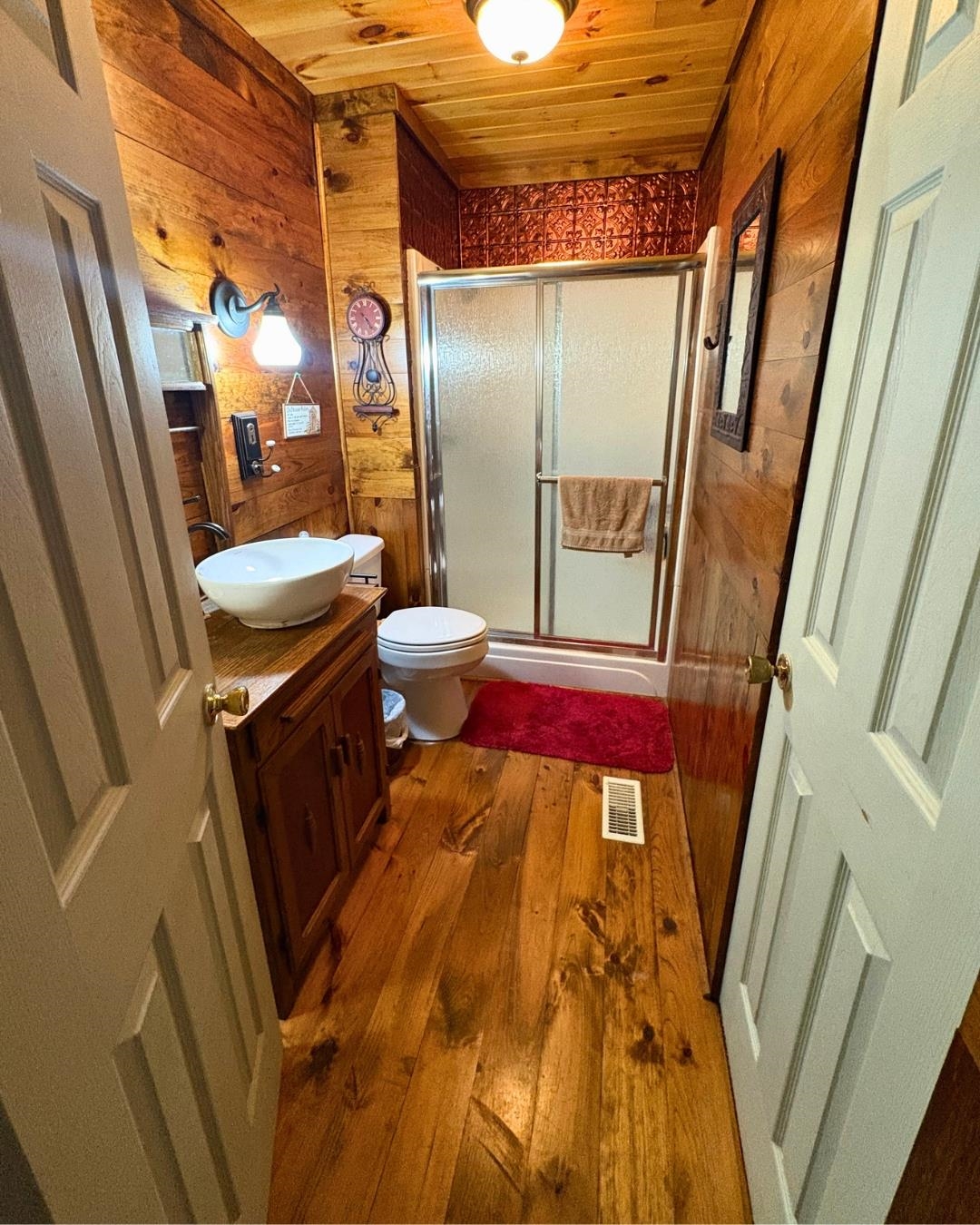772 Rushing Road Michie, TN 38357 - Photo 13 of 19 Bathroom featuring wood-finish wall and ceiling panels, a shower enclosure with sliding glass doors, a vanity with a vessel sink, and wide plank wood-finish flooring