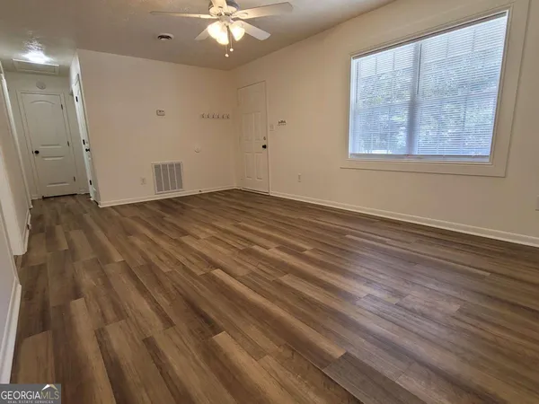 an empty room with wooden floor and windows