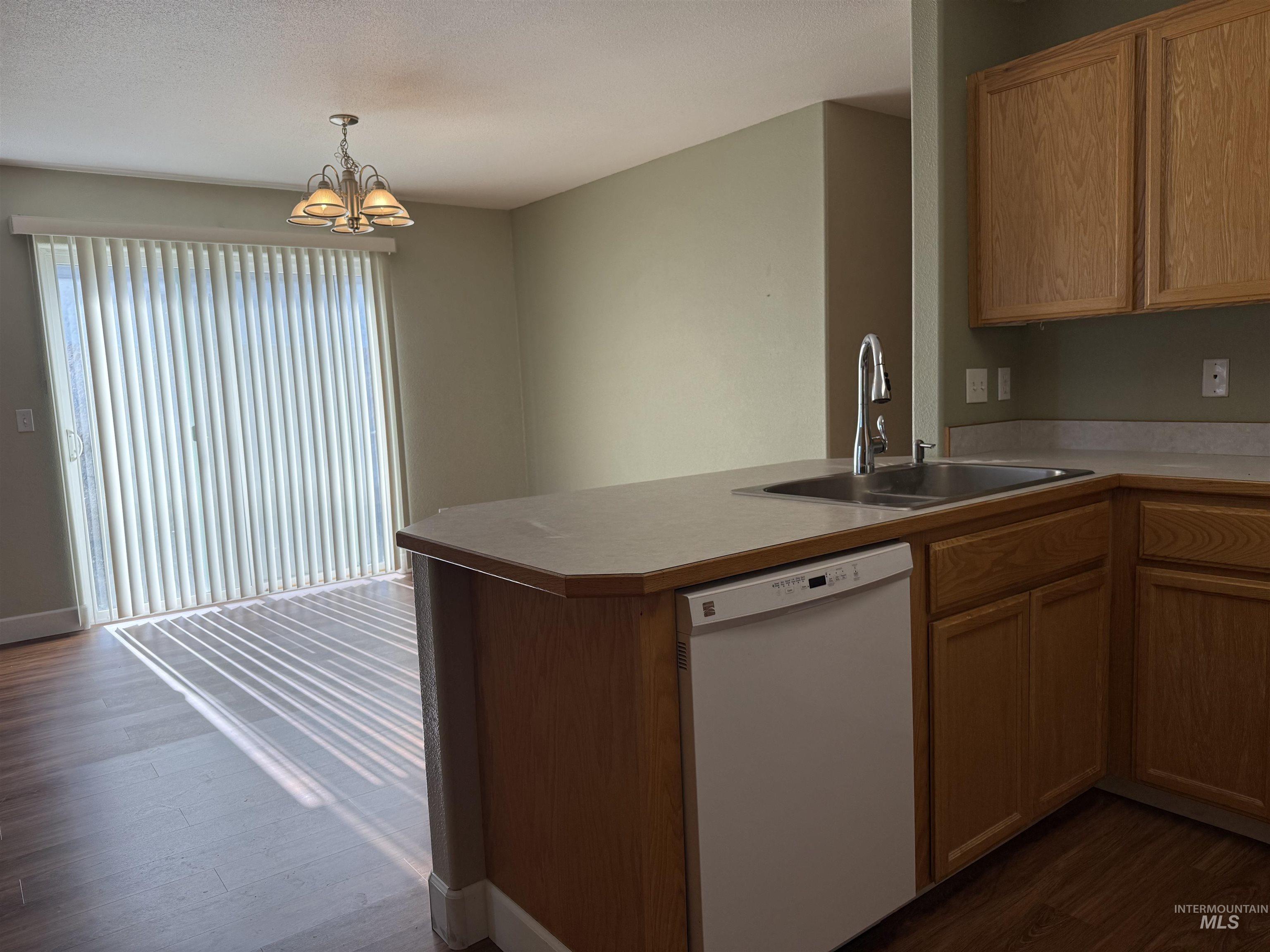 257 Pintail Lane Moscow, ID 83843 - Photo 6 of 28 Kitchen with white dishwasher, dark wood-style floors, light countertops, hanging lights, and a peninsula