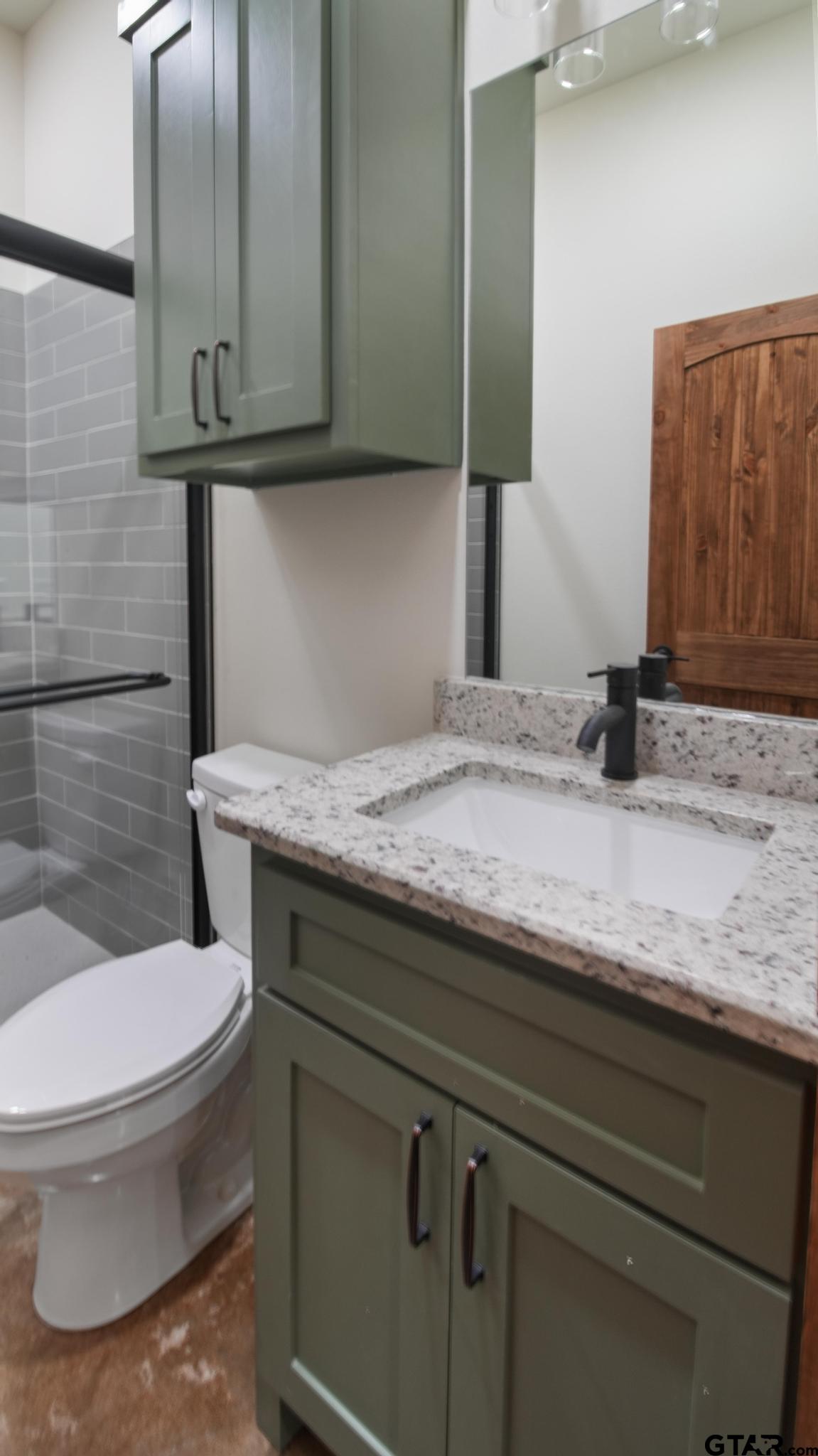 22522 Pine Street Flint, TX 75762 - Photo 29 of 39 a bathroom with a granite countertop sink a toilet and mirror