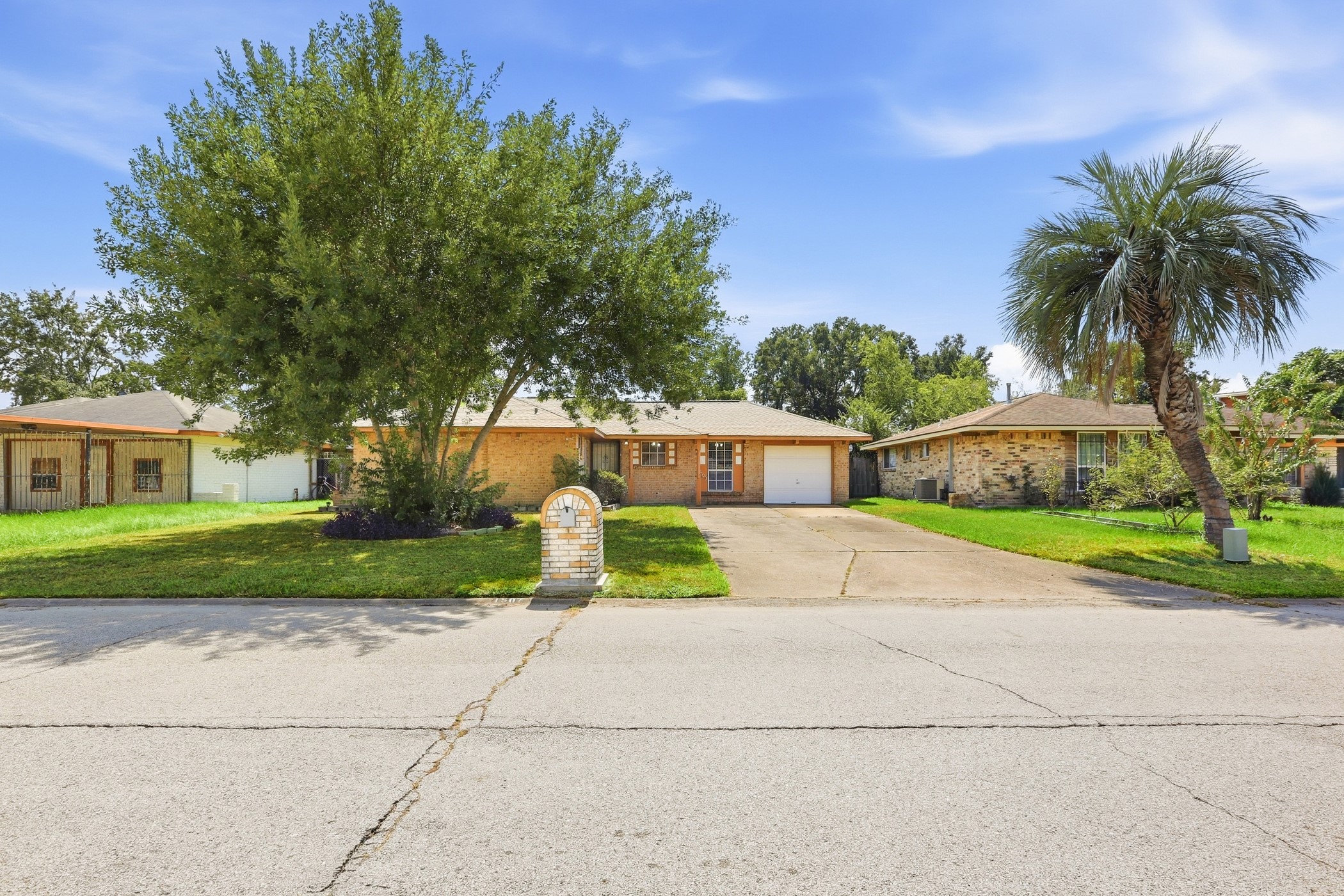 1507 Willow Rock Road Houston, TX 77088 - Photo 2 of 27 Curb view with a brick mailbox, mature shade tree, palm accent, and an extended concrete driveway for additional parking.