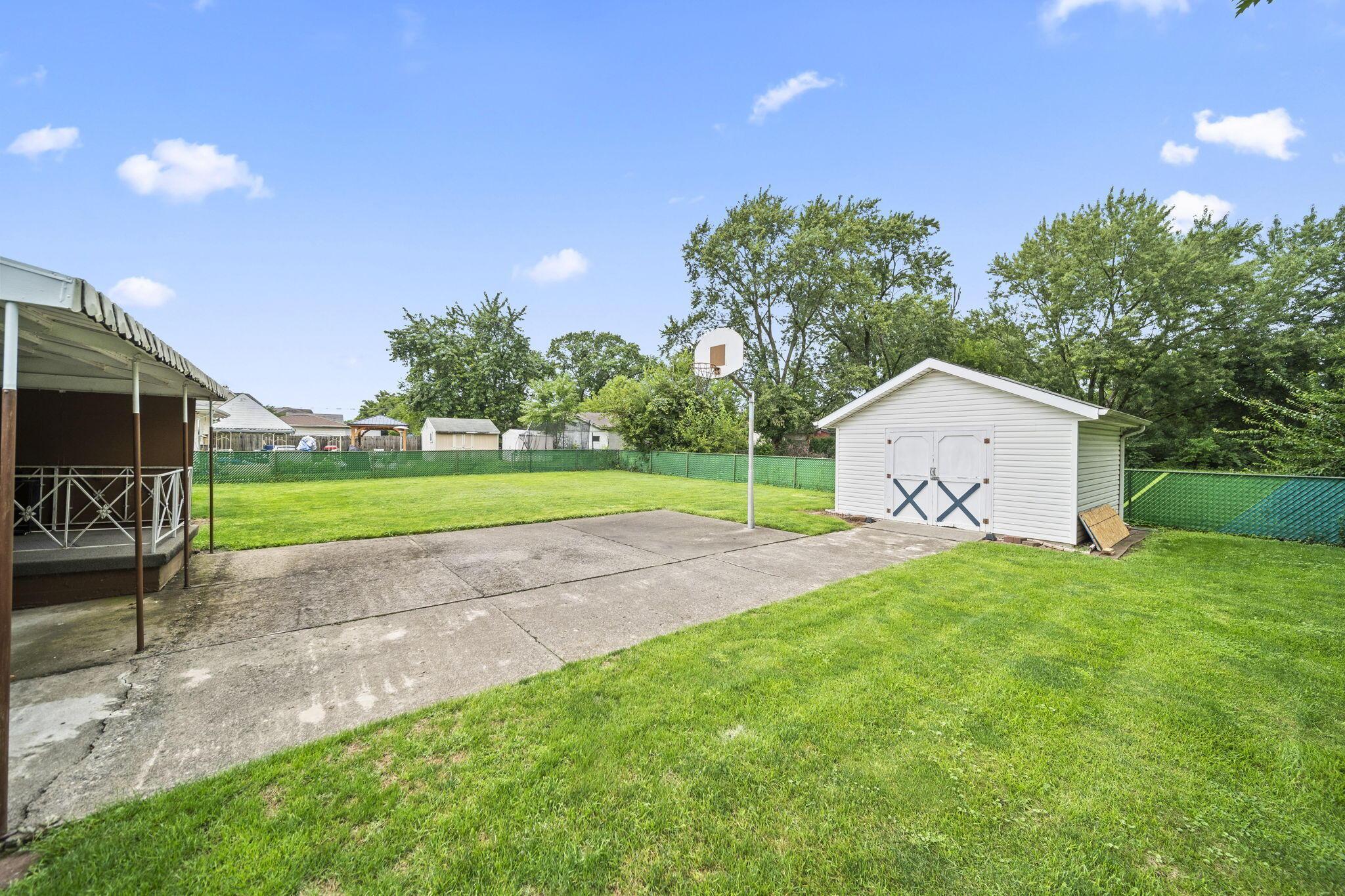 3496 Wicklow Road Columbus, OH 43204 - Photo 42 of 53 Expansive green space featuring a concrete pad, a freestanding storage shed, and a green chain-link fence