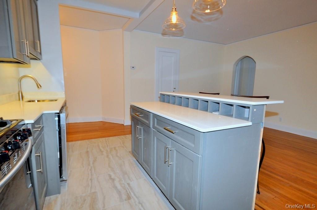 69 Harney Road, Unit 3A Scarsdale, NY 10583 - Photo 13 of 22 Renovated Kitchen with center Island, pendent lighting, Granite Counters, Stainless Steel Appliance including a dishwasher, range, microwave and refrigerator. The wall separating the eat-in-kitchen and living room have been removed and a center Island installed with electric and USB outlets installed to create an open concept.