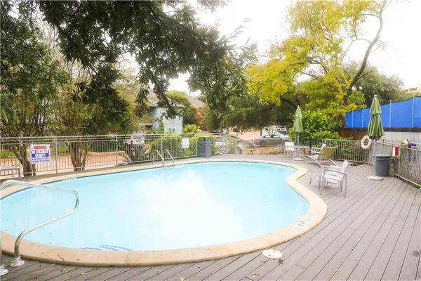 a view of a swimming pool with a patio and wooden fence