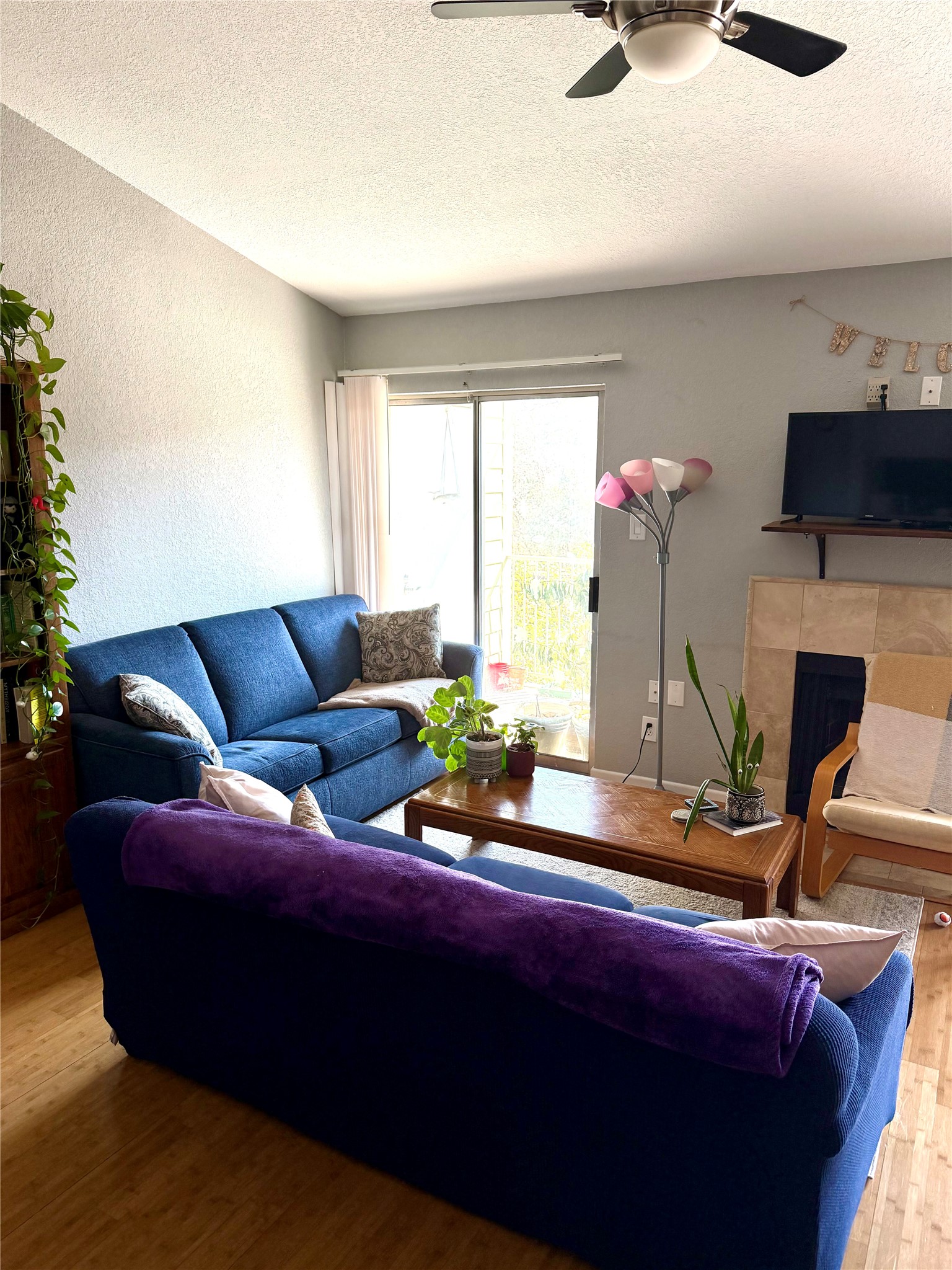 3204 Menchaca Road, Unit 204 Austin, TX 78704 - Photo 6 of 18 Living area featuring wood finished floors, a fireplace, ceiling fan, a textured ceiling, and a textured wall