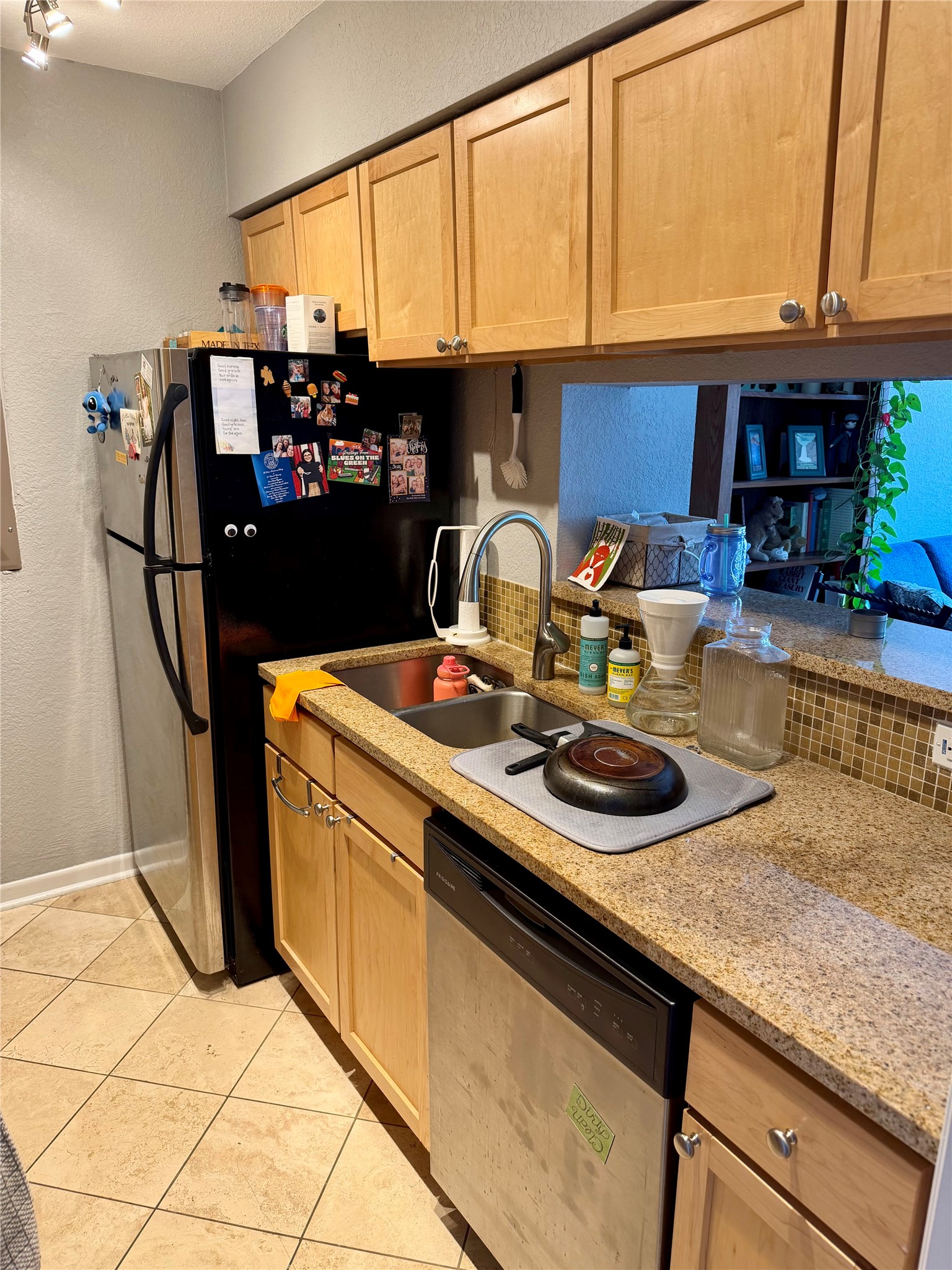 3204 Menchaca Road, Unit 204 Austin, TX 78704 - Photo 9 of 18 Kitchen featuring a textured wall, light wood finish cabinets, light stone counters, stainless steel appliances, and light tile patterned floors
