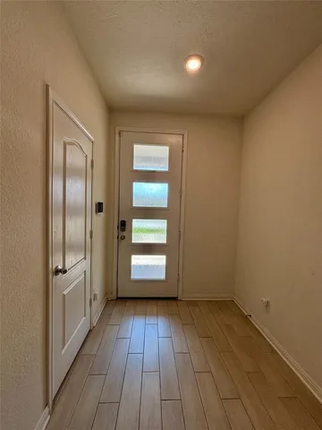 an empty room with wooden floor cabinet and windows