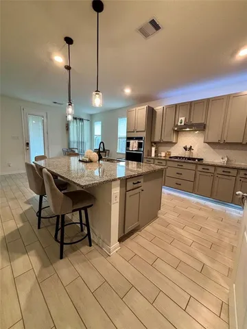 a kitchen with stainless steel appliances kitchen island granite countertop a sink a stove a dining table and chairs